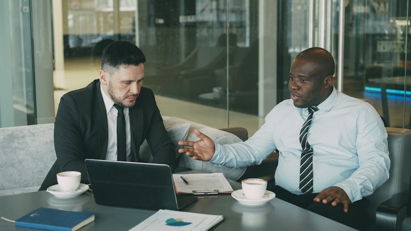 Two business people discussing deal documents over coffee